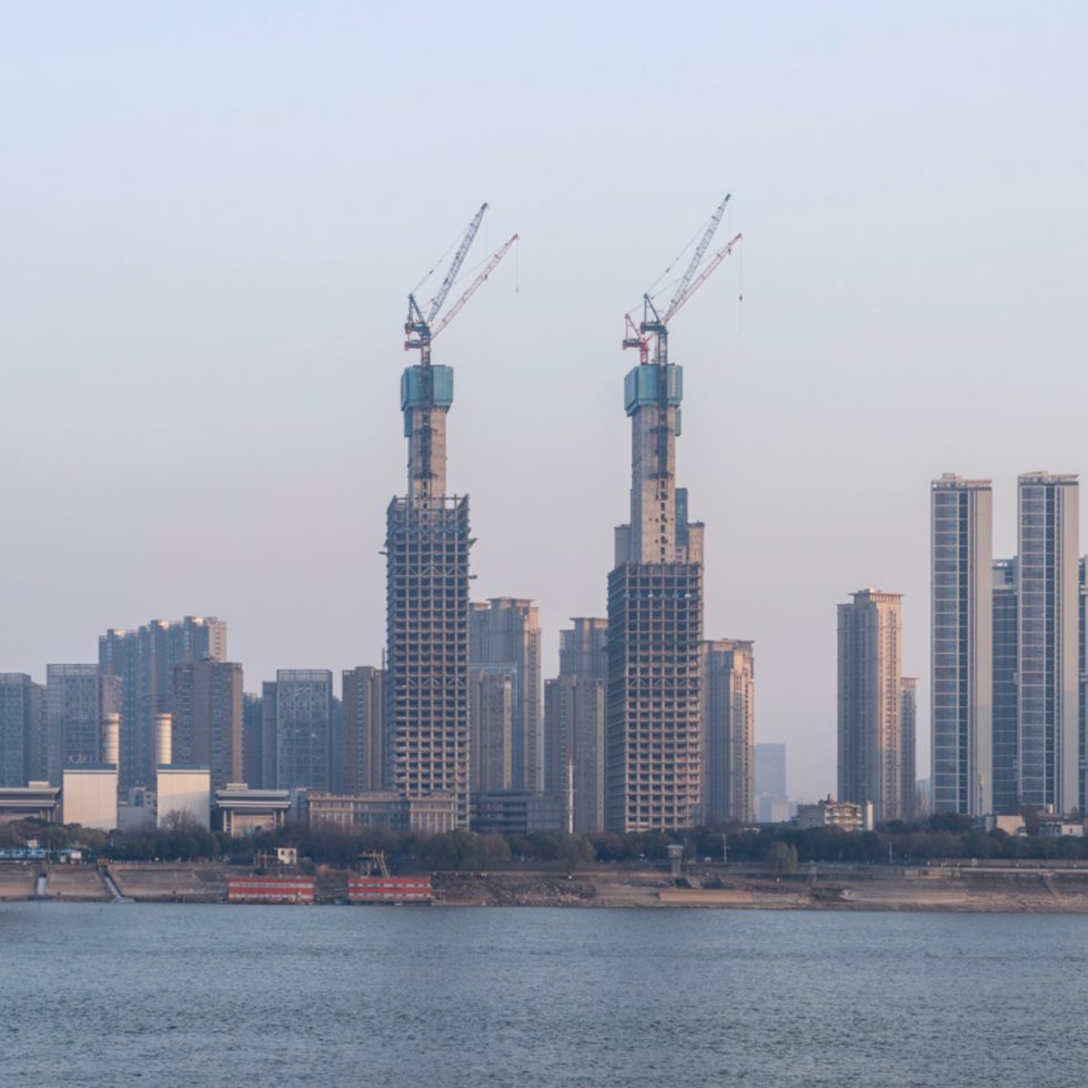 This is a photograph of two skyscrapers under construction with cranes at the top of each.